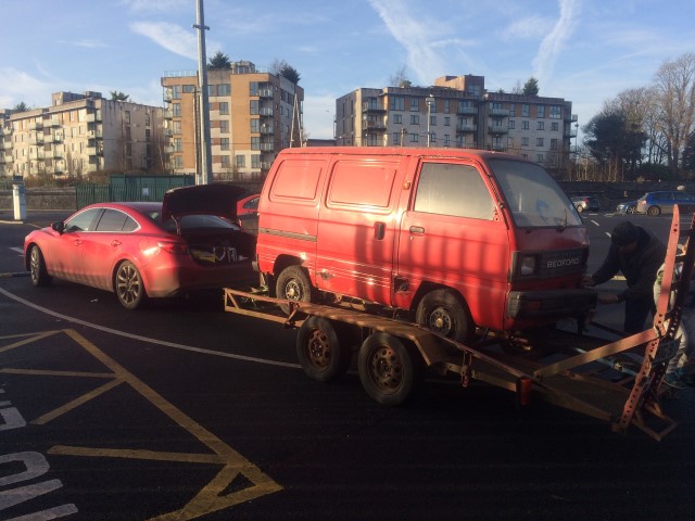 Red Bedford Rascal loaded onto car transporter for restoration
